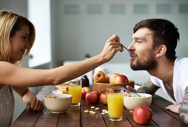 una mujer alimenta a un hombre con nueces para aumentar la potencia